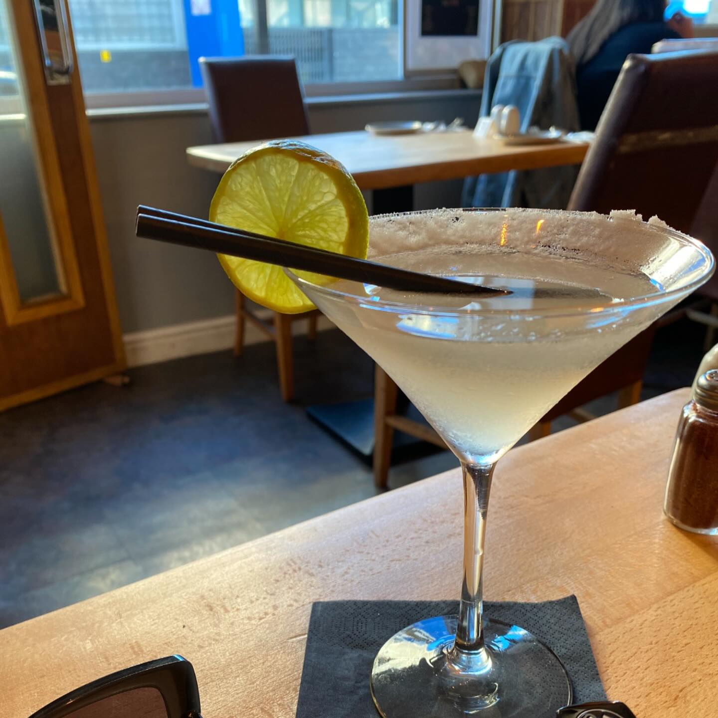 A vibrant cocktail served in a glass with a salt rim and a lime wedge.