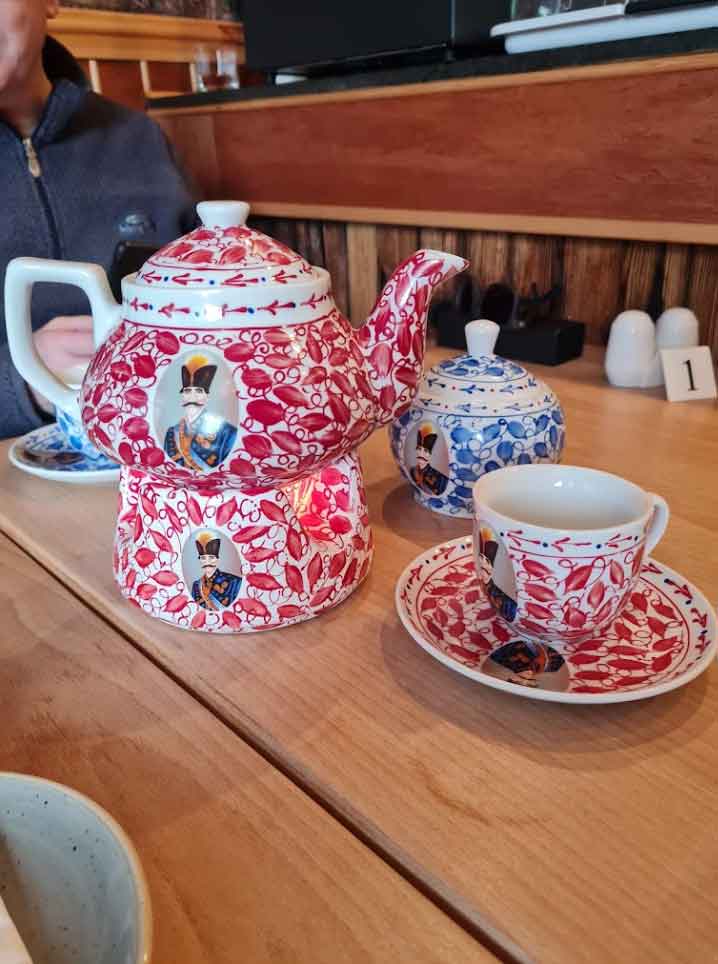 Persian tea set with decorative red teapot, matching sugar bowl, and cups.